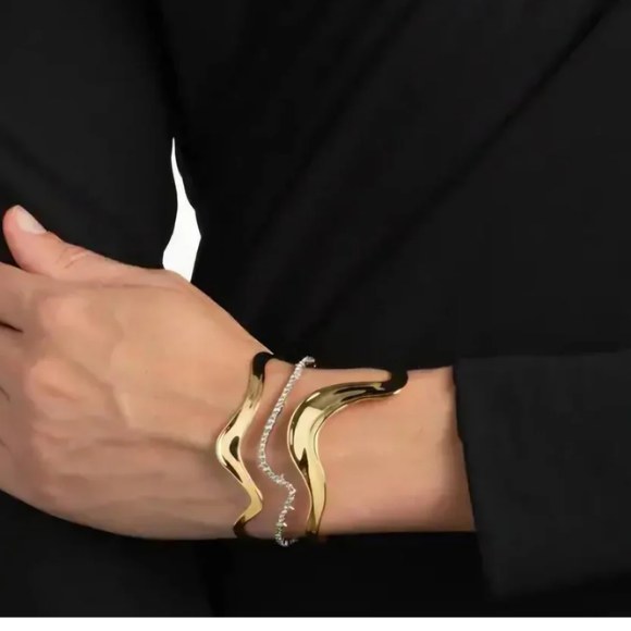 Gold tone wave cuff bracelet with a silver chain accent