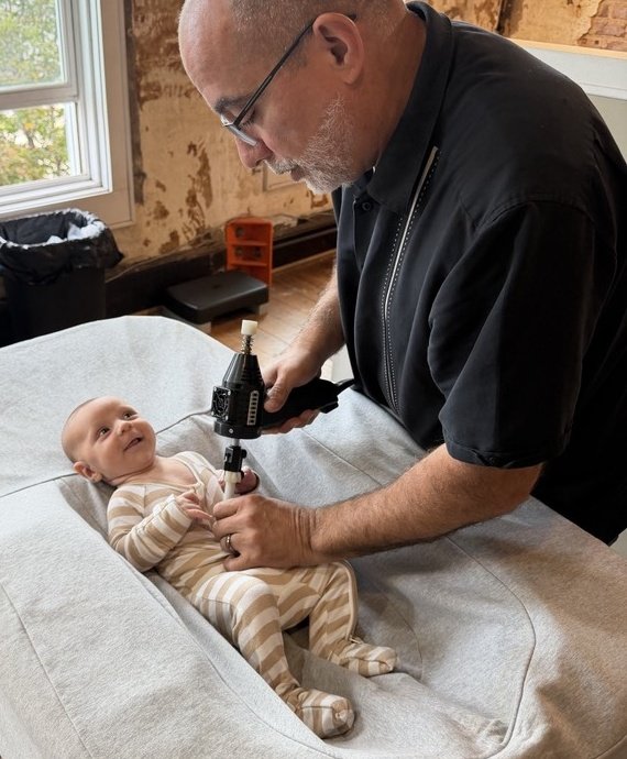 Dr. Chris providing instrument-assisted chiropractic care to an infant