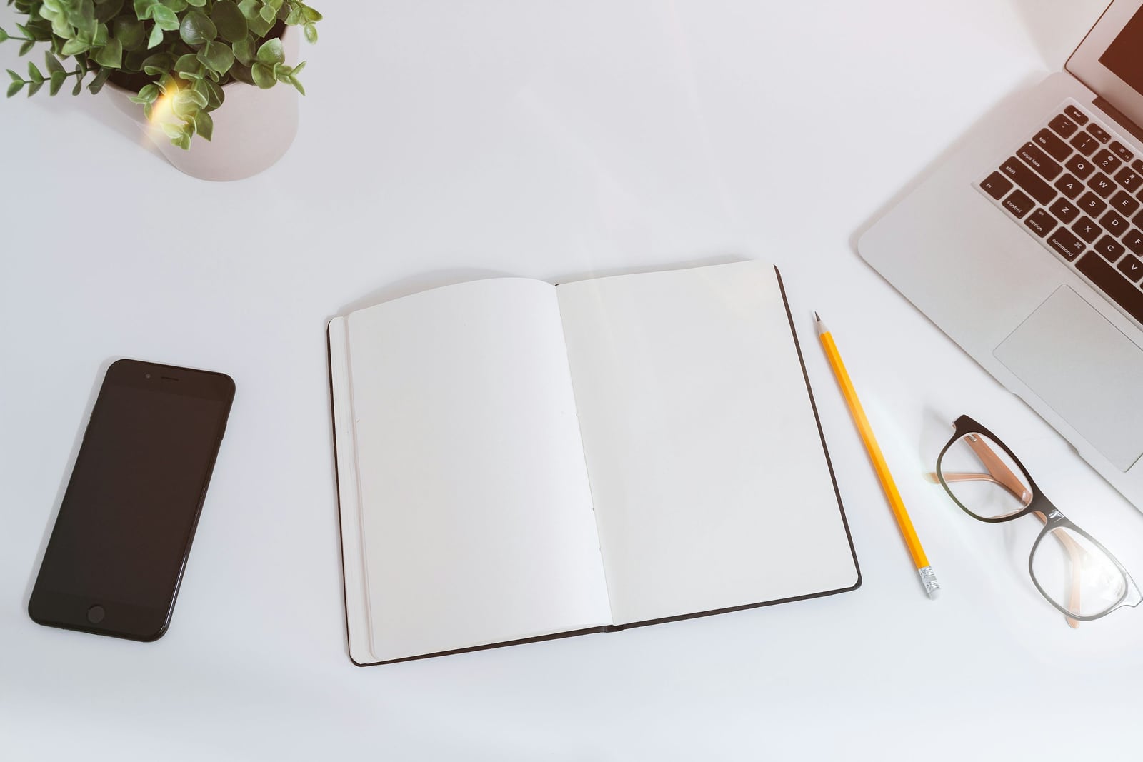 Blank notebook, pencil, and glasses on a desk
