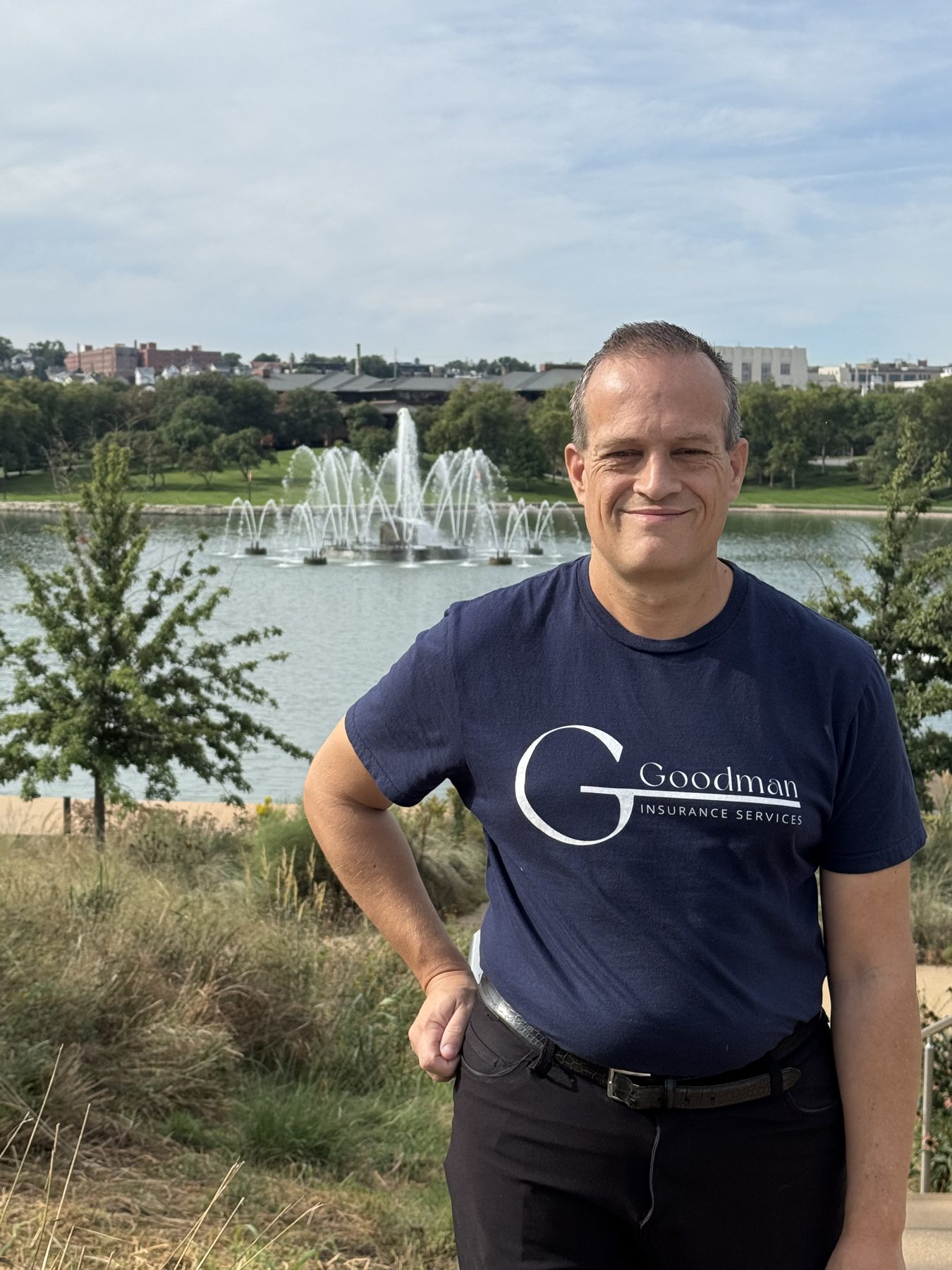 Goodman Insurance Services team member wearing a navy agency shirt beside the fountains