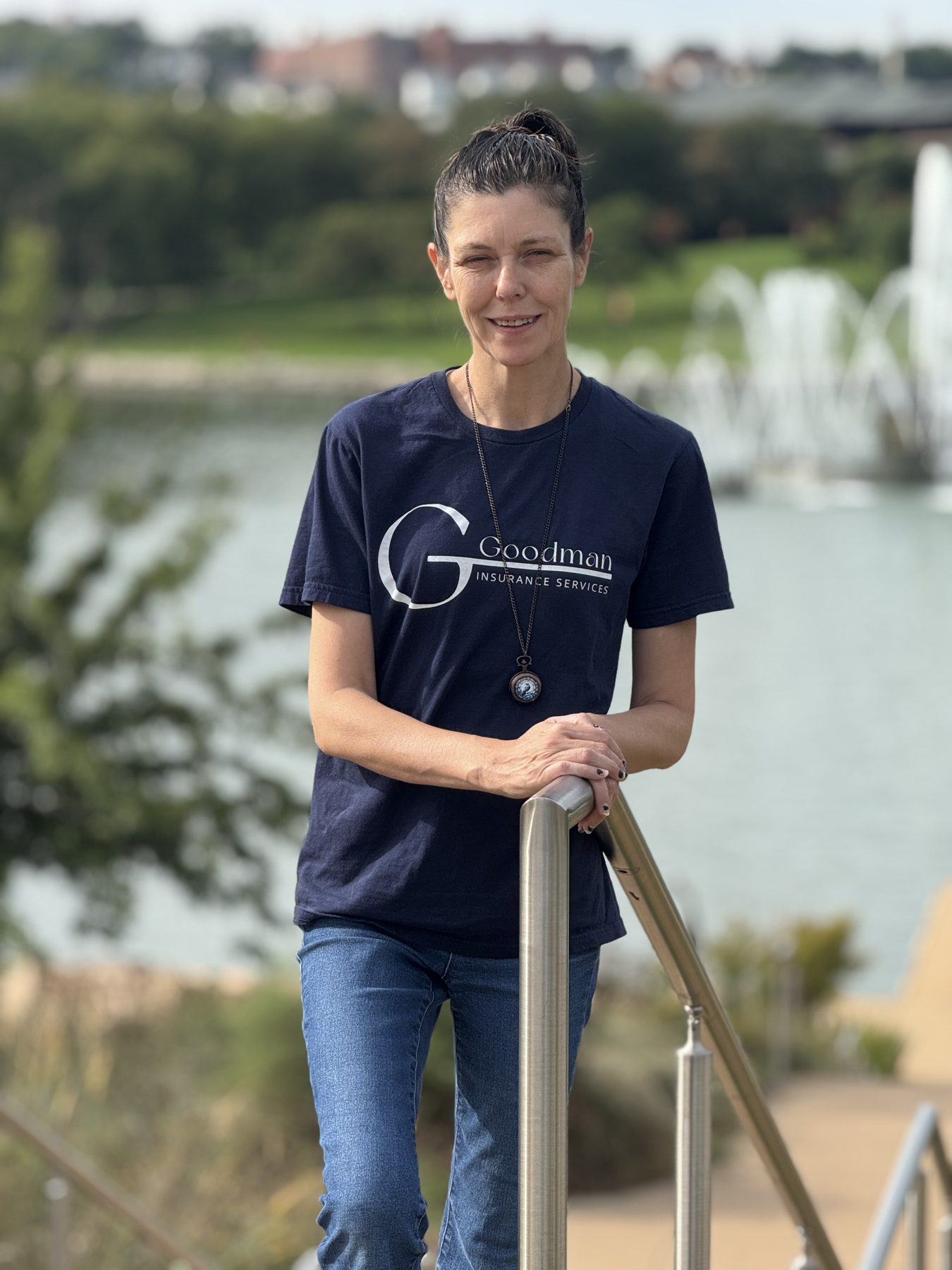 Goodman Insurance Services team member wearing a navy agency shirt by the waterfront railing