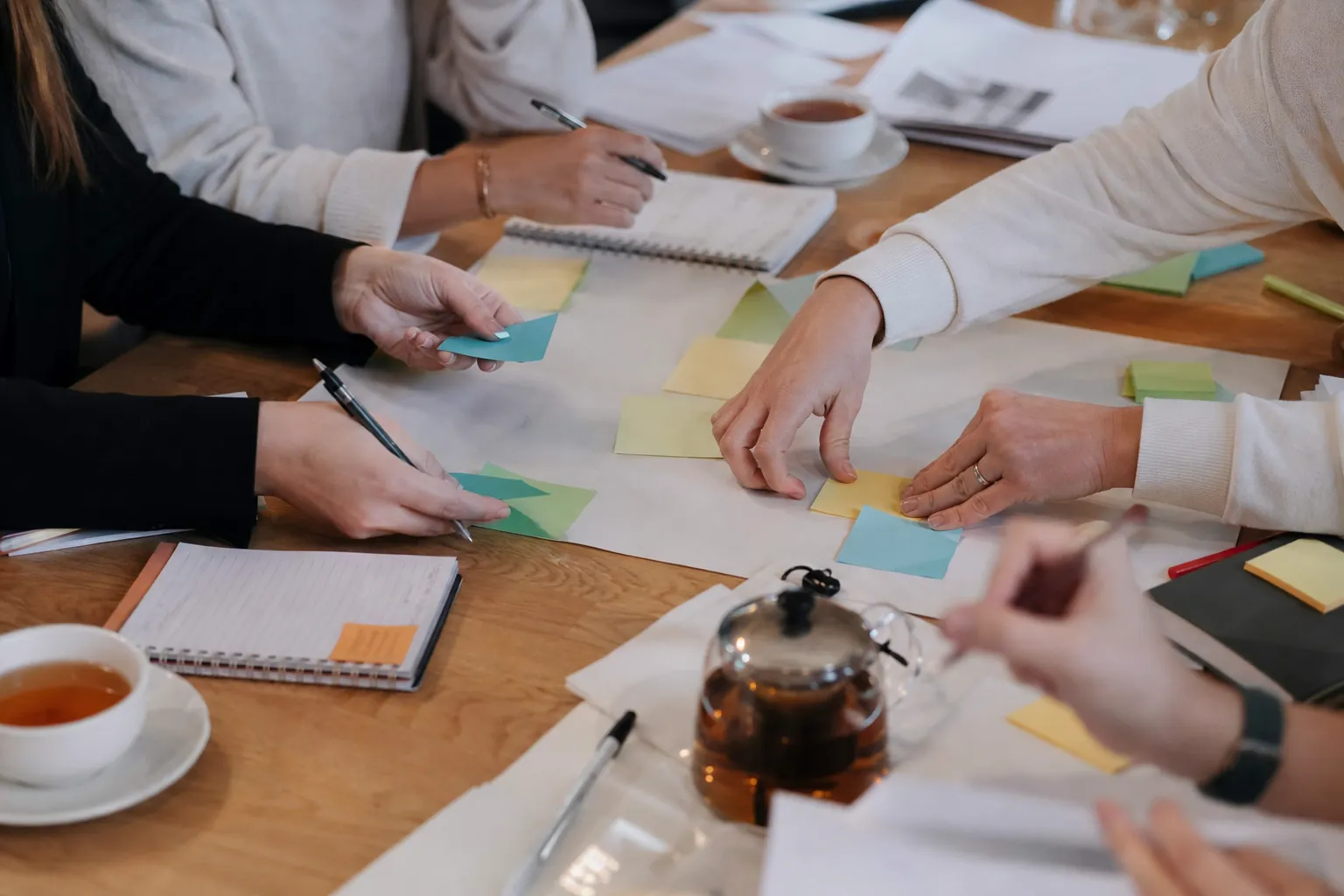 Hands planning together with notebooks and sticky notes