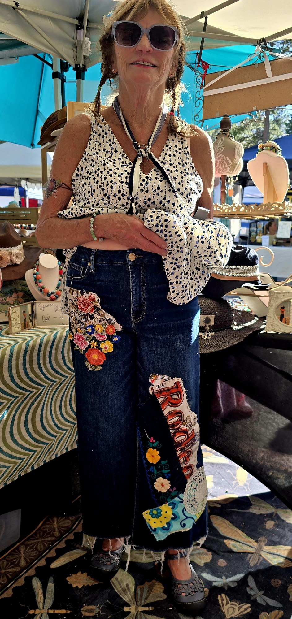 A handmade denim skirt with floral fabric and appliqué details at an outdoor art market