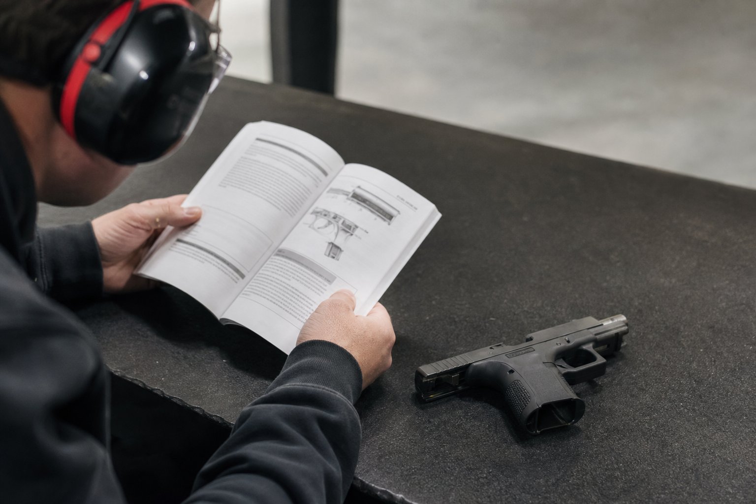 Student reviewing a handgun owner manual at a range bench