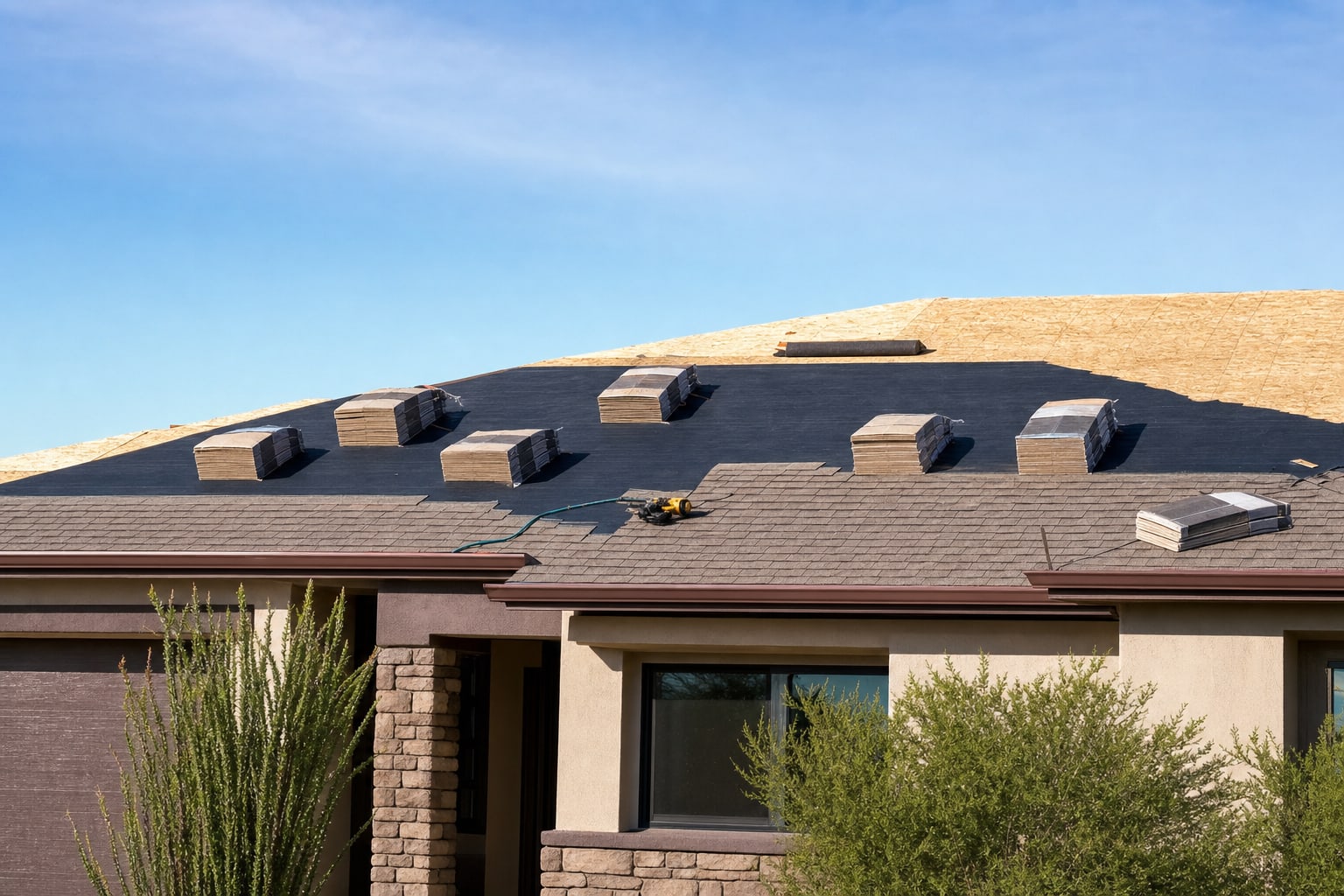 Residential roof replacement in progress with new underlayment and staged shingles