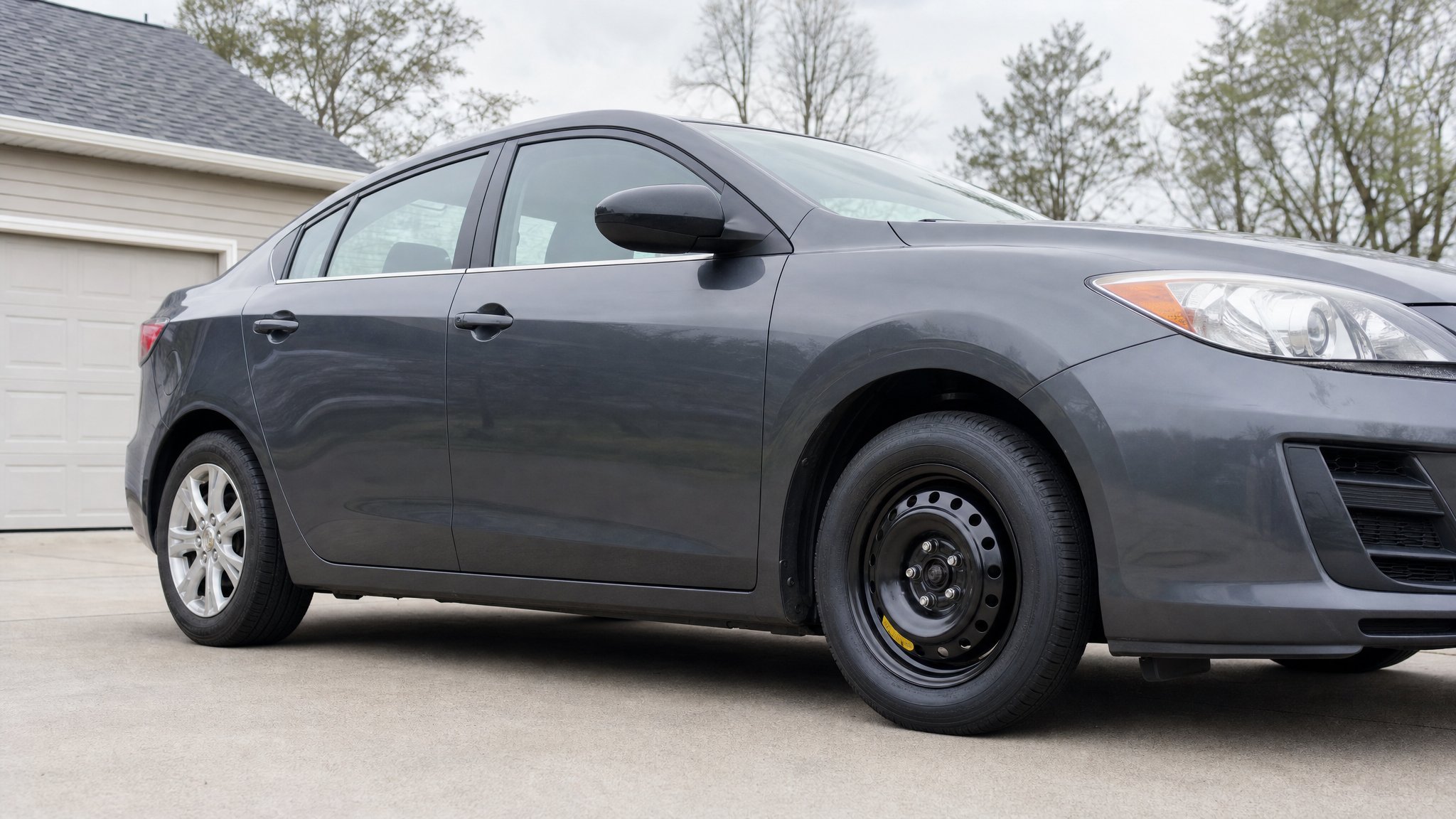 Compact temporary spare tire installed on a parked sedan