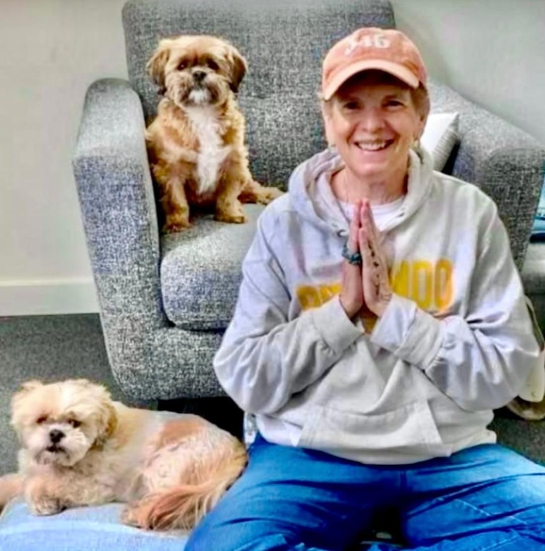 A woman meditating peacefully at home with dogs nearby