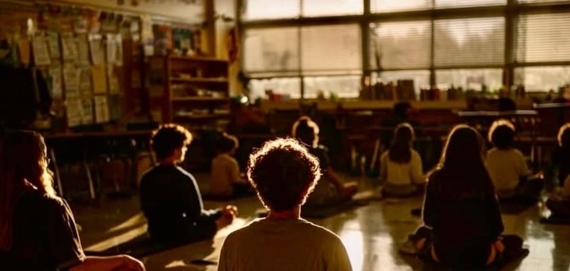 Children sitting quietly together in a classroom, facing the window
