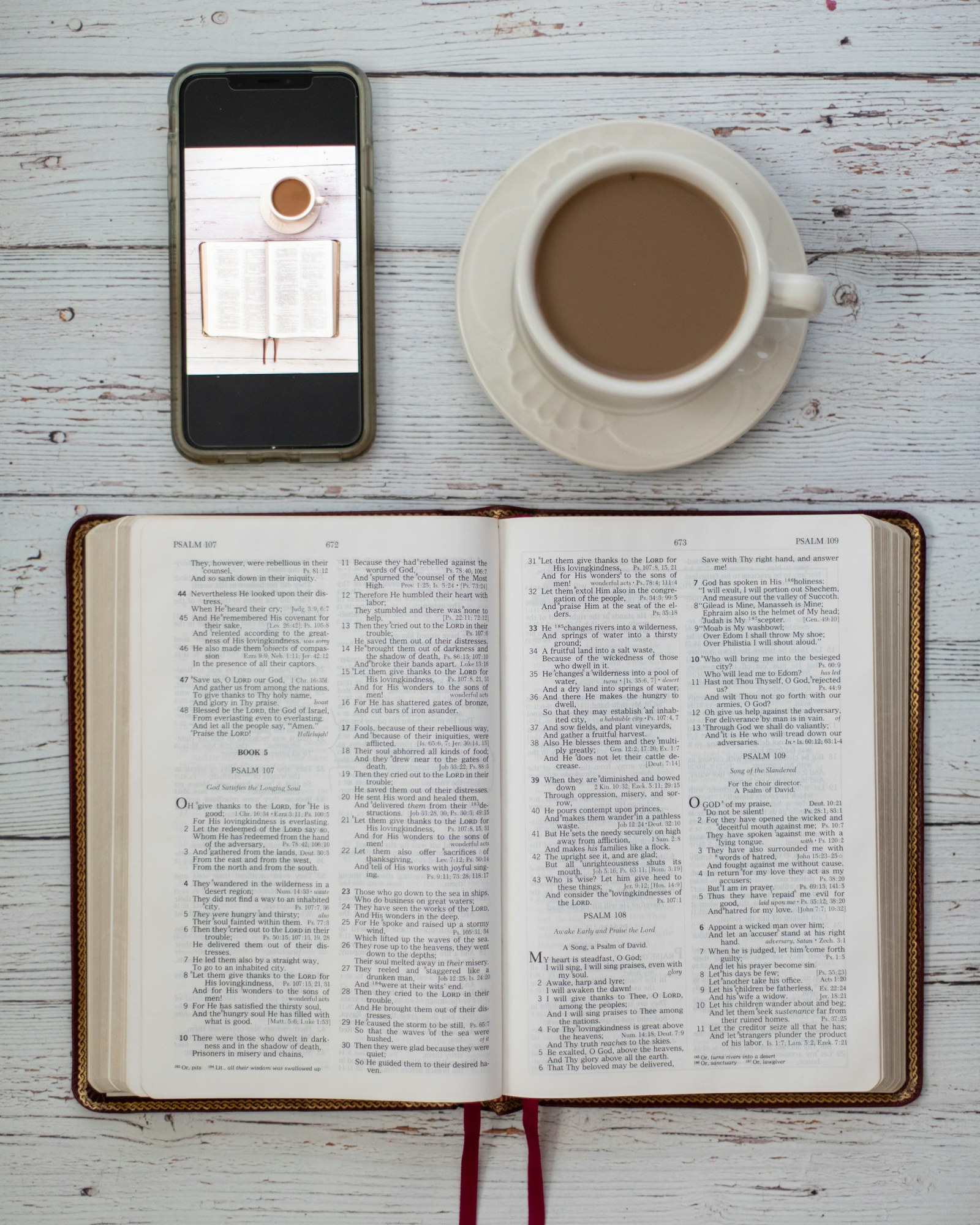 Open Bible with a coffee cup and phone on a table