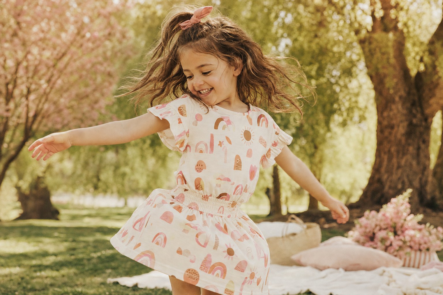 Child spinning in a playful printed outfit outdoors