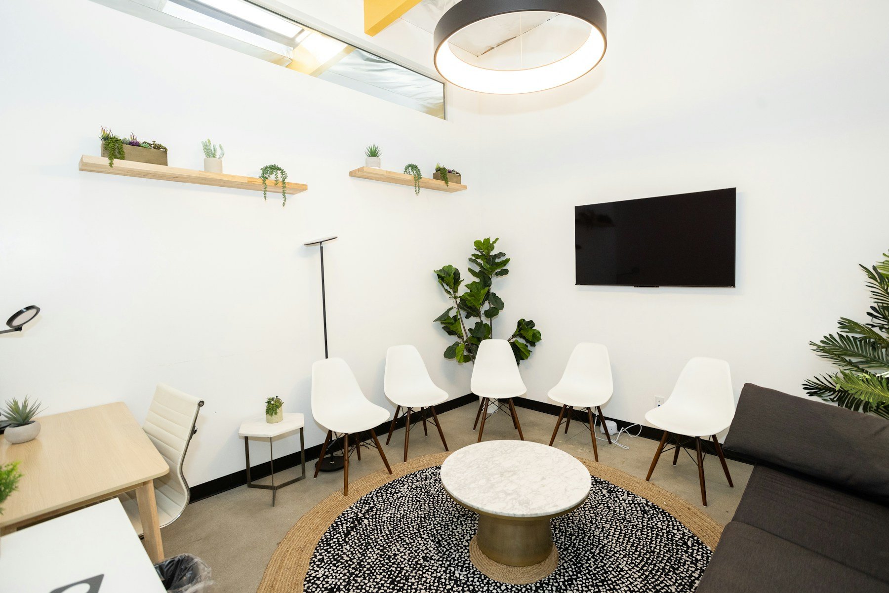 Empty white chairs and plants in a bright waiting room