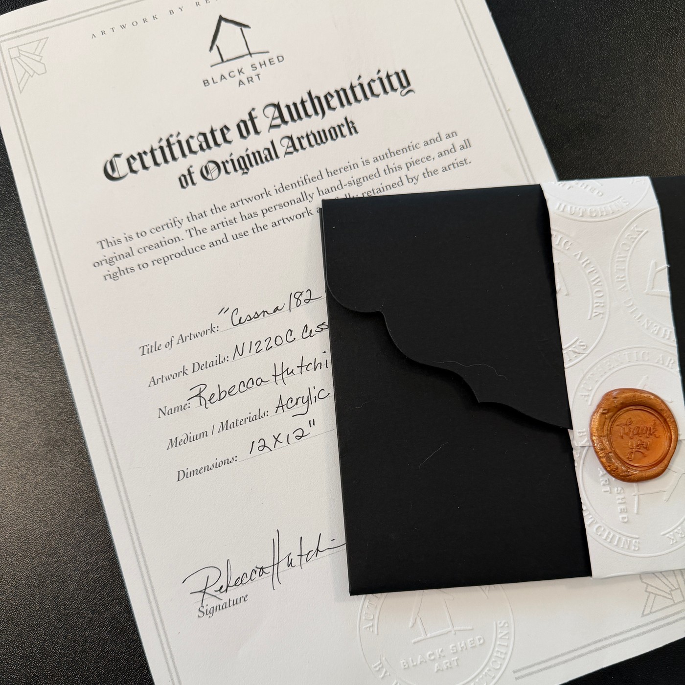 Rebecca Hutchins’ signed Black Shed Art certificate of authenticity, shown with a black envelope and a wax-sealed card