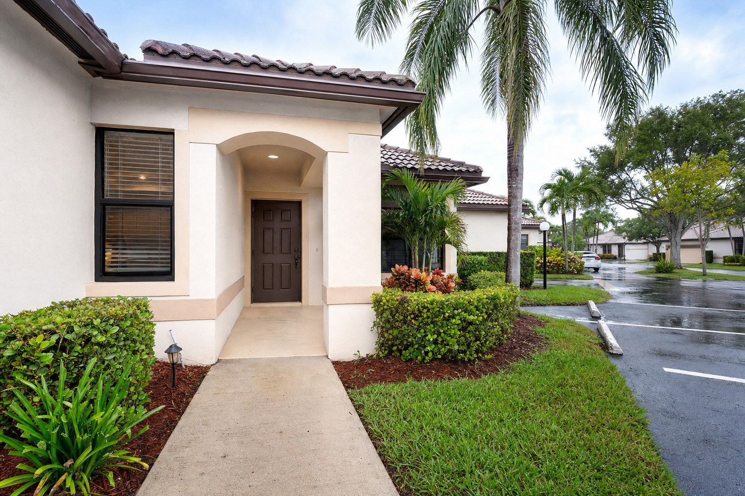 Villa entry walkway, parking, and landscaping in a South Florida active-adult community