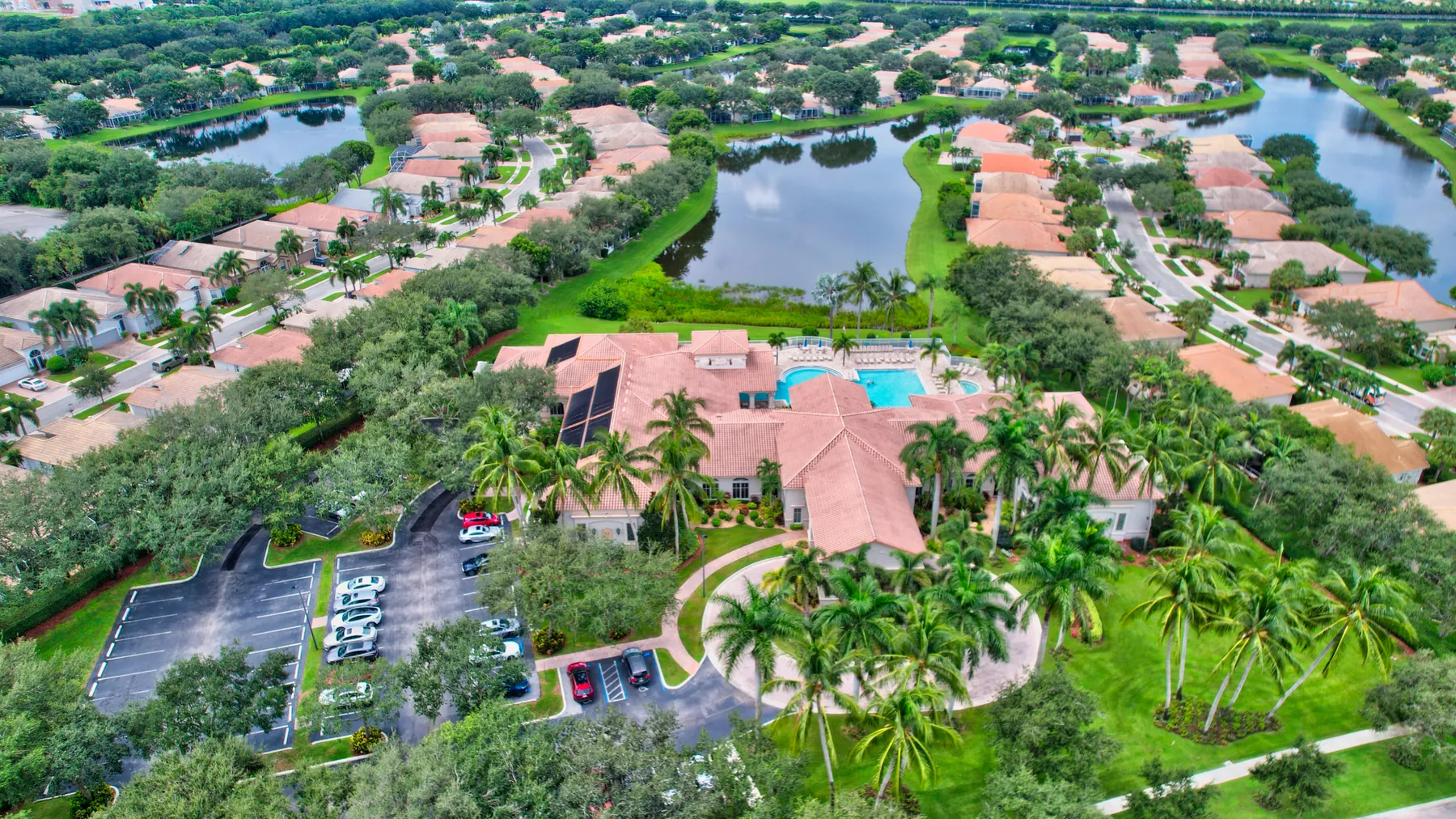 Aerial view of a clubhouse, pool, and homes in a Palm Beach County community