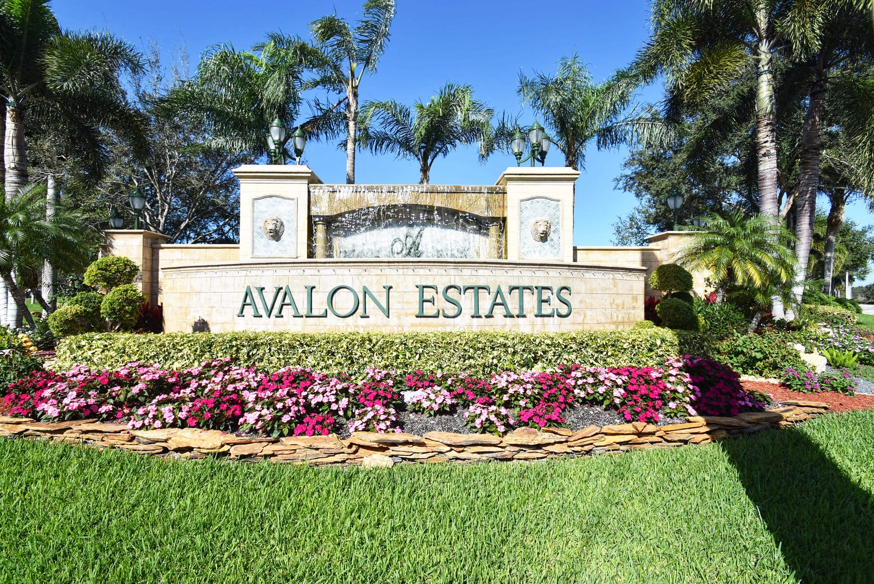 Avalon Estates entrance sign framed by palm trees and colorful landscaping