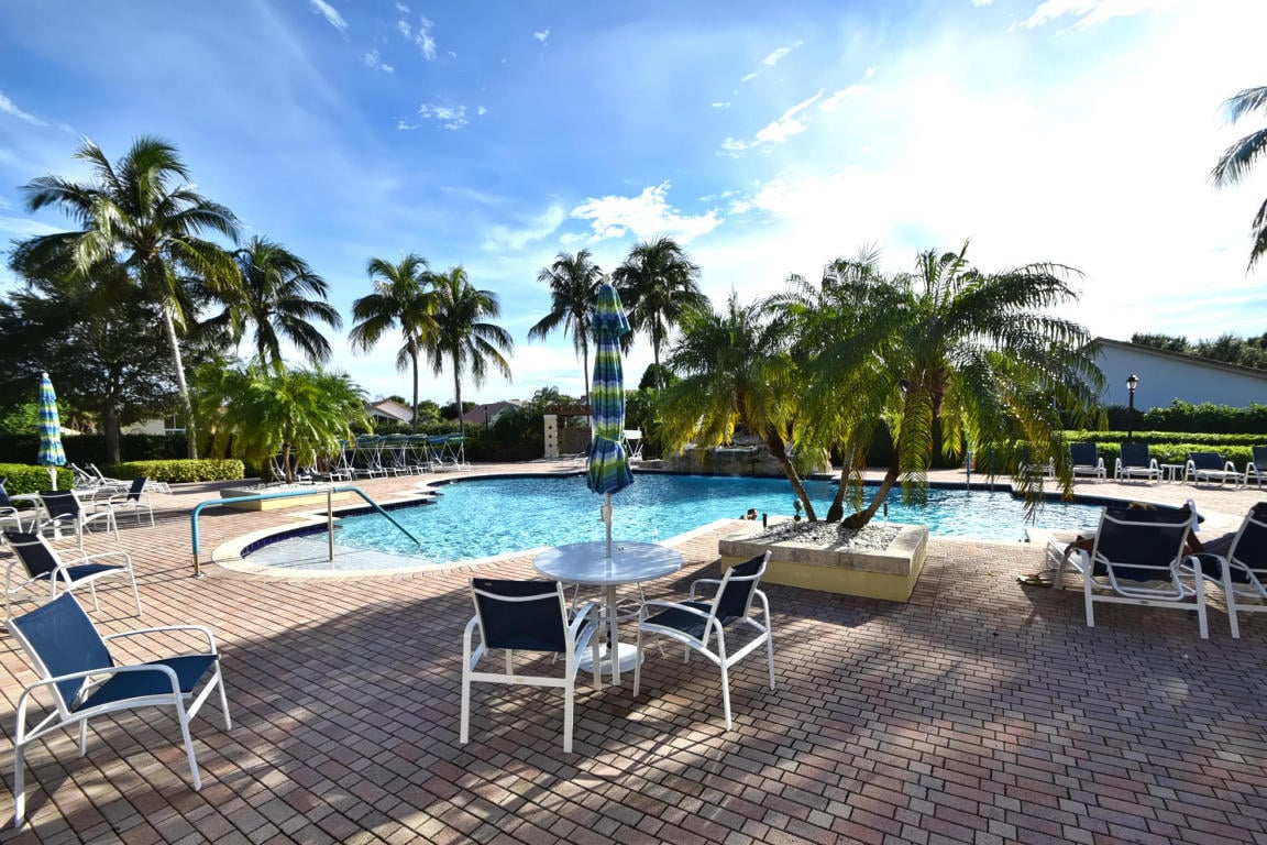 Outdoor community pool beside palm trees in a South Florida active-adult neighborhood