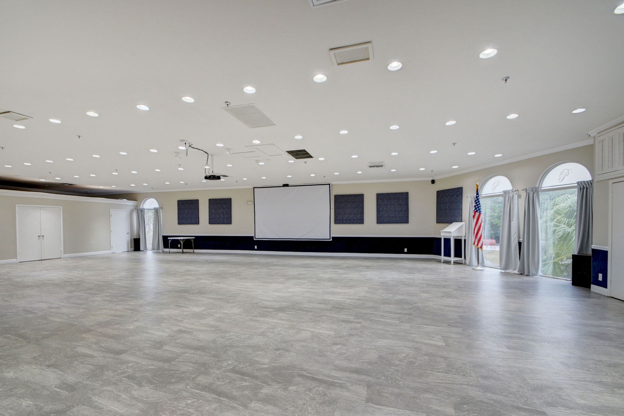 Open clubhouse ballroom at Poinciana with event space and presentation screen