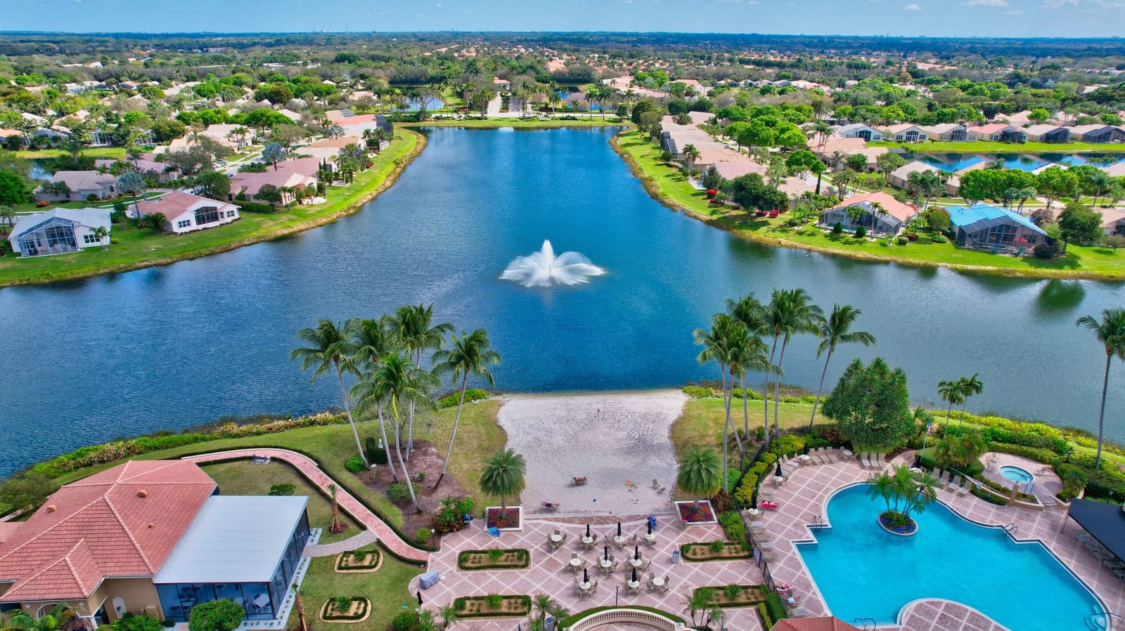 Aerial view of a landscaped South Florida 55+ community with lakes and single-story homes