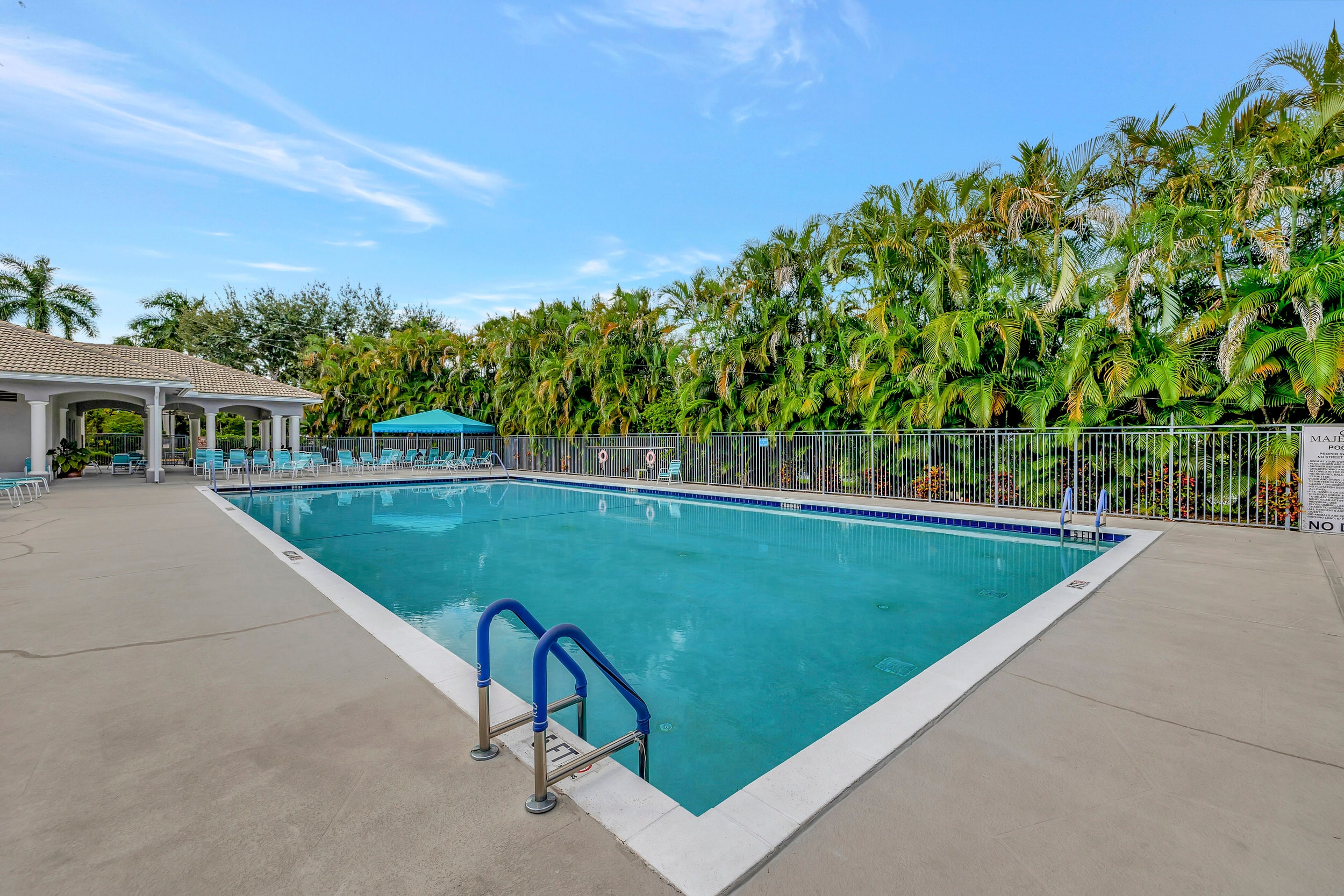 Majestic Isles outdoor swimming pool with wide sun deck, lounge chairs, palm trees, and clubhouse