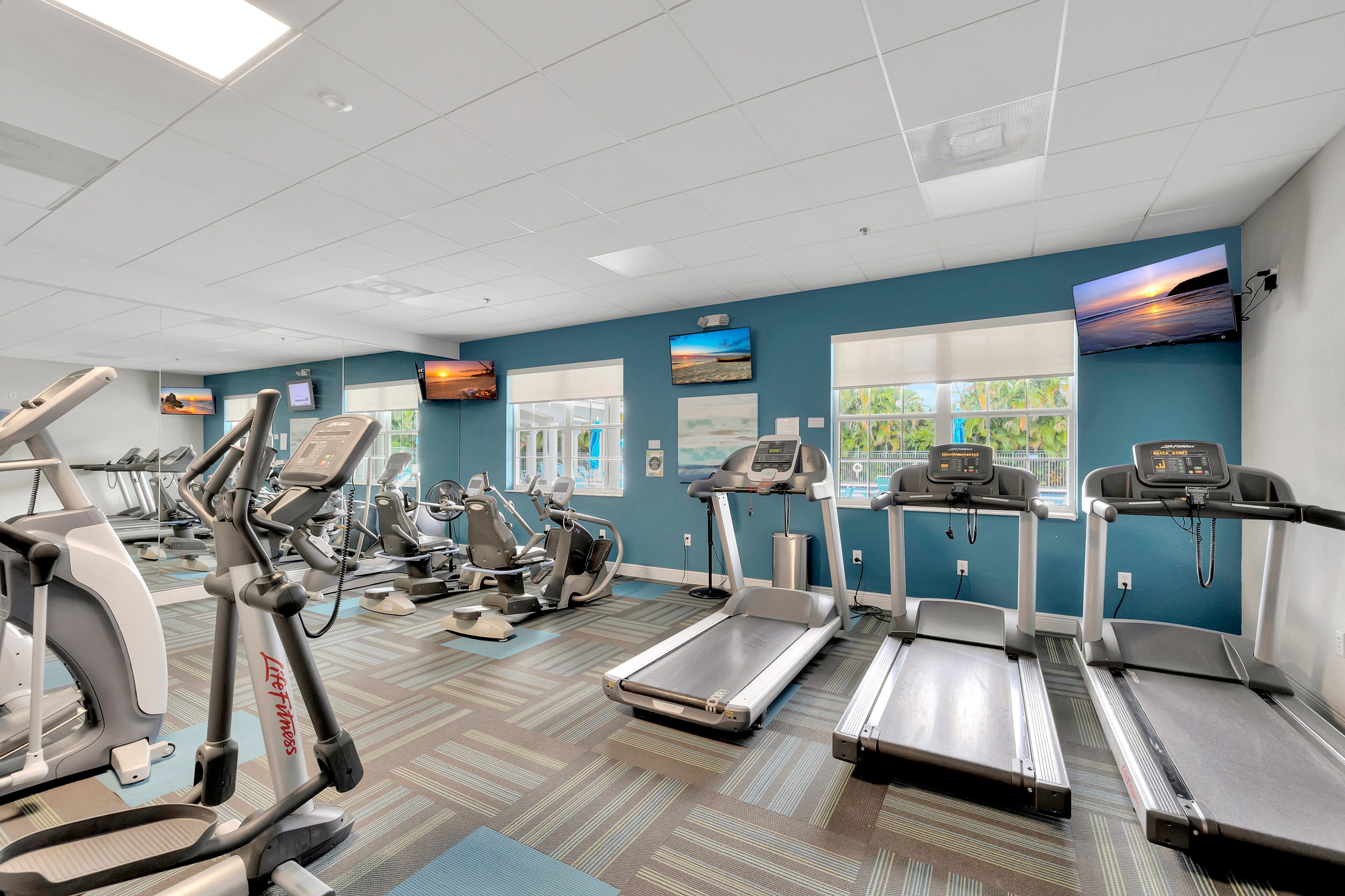 Majestic Isles fitness center with treadmills, strength equipment, and bright blue accent walls