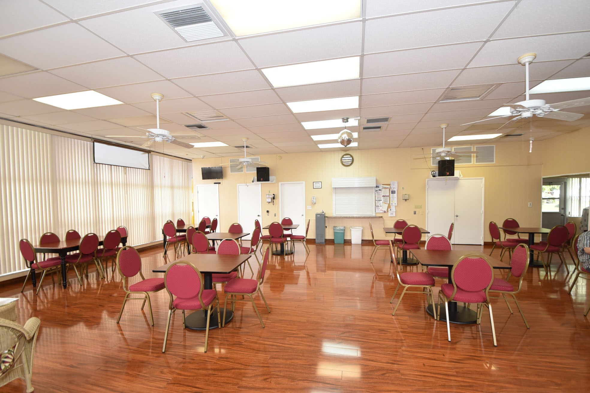 Palm Beach Leisureville clubhouse social room with tables, chairs, and polished wood floor