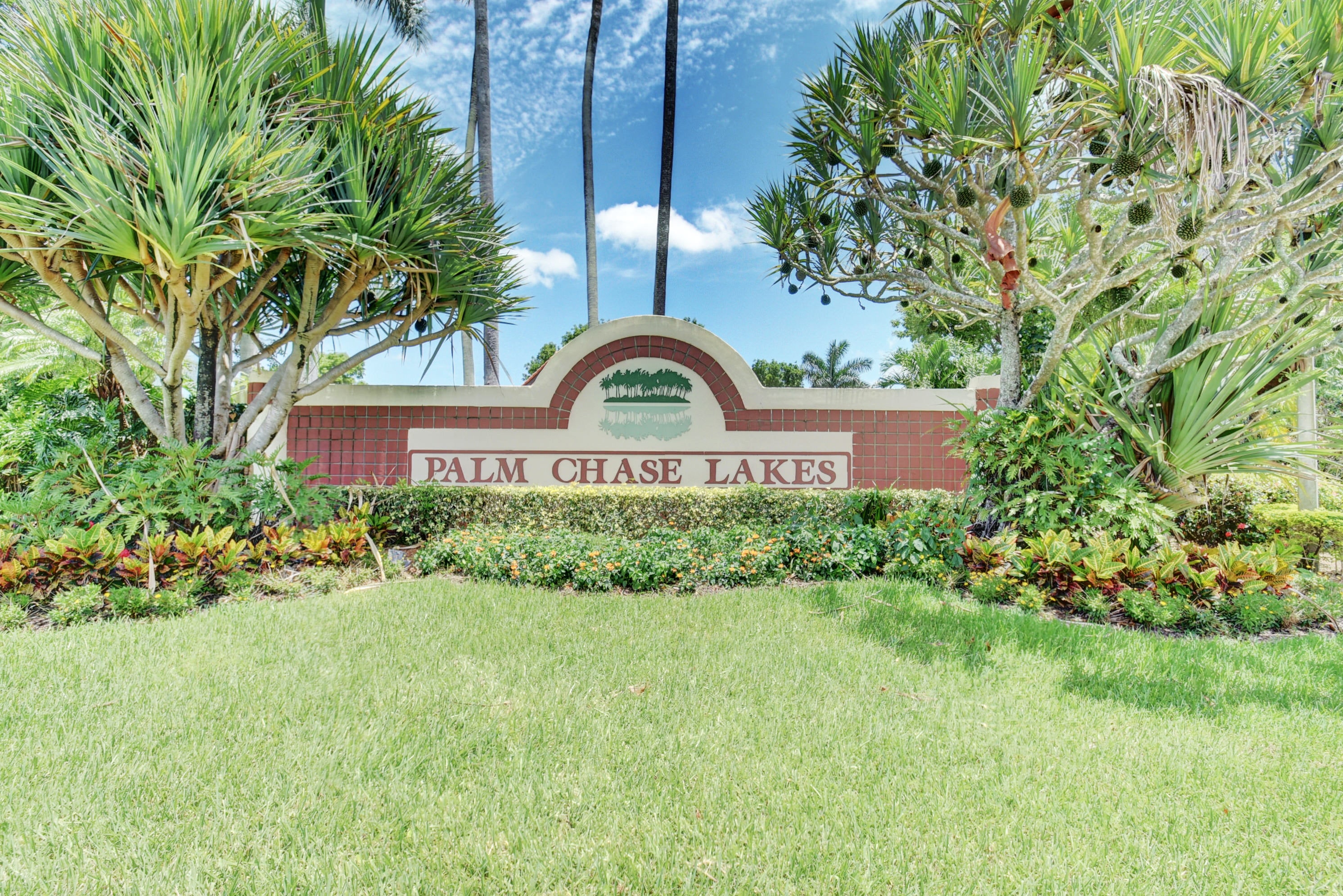 Palm Chase Lakes community entrance sign framed by lush tropical landscaping