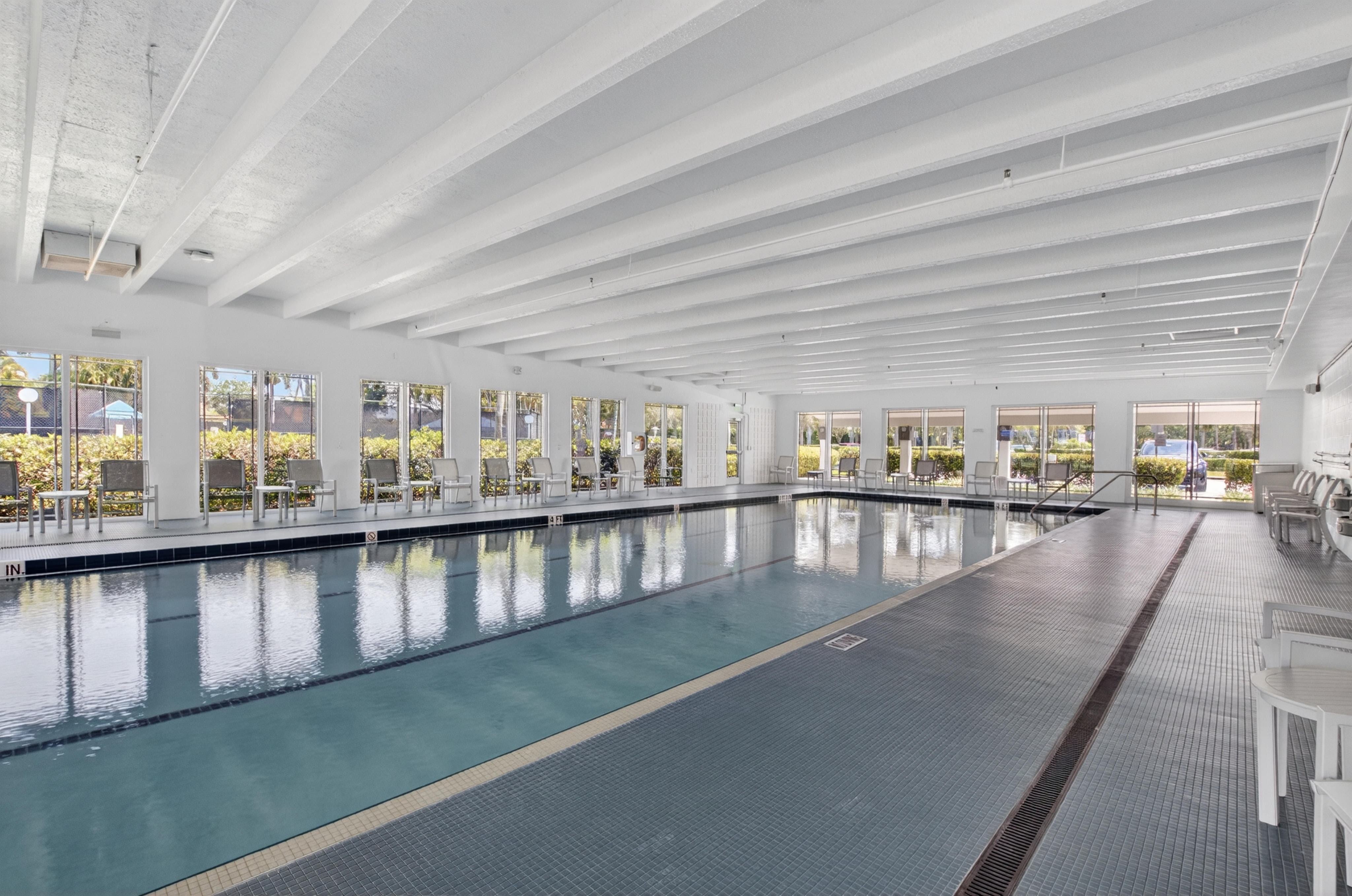 Indoor Palm Isles swimming pool with broad windows and poolside seating