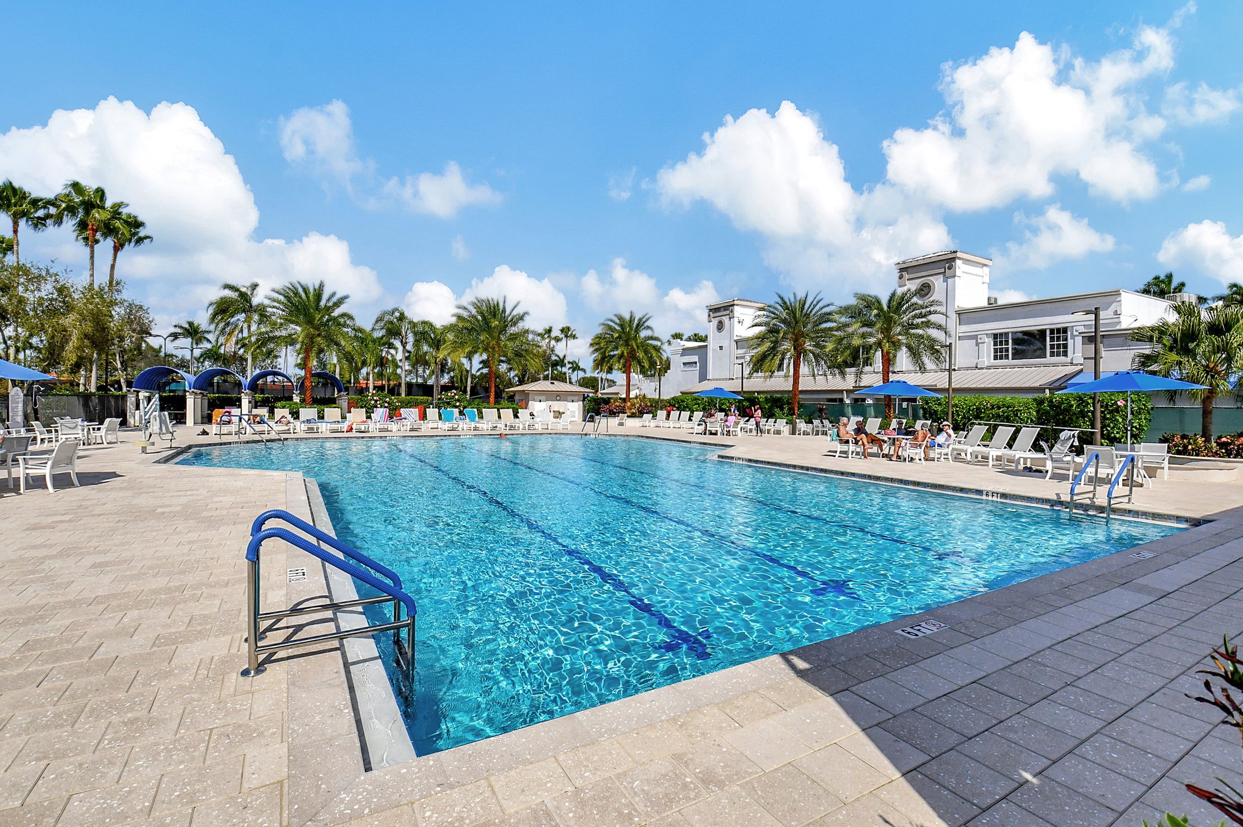 Palm Isles outdoor pool surrounded by palms, lounge chairs, and the community clubhouse