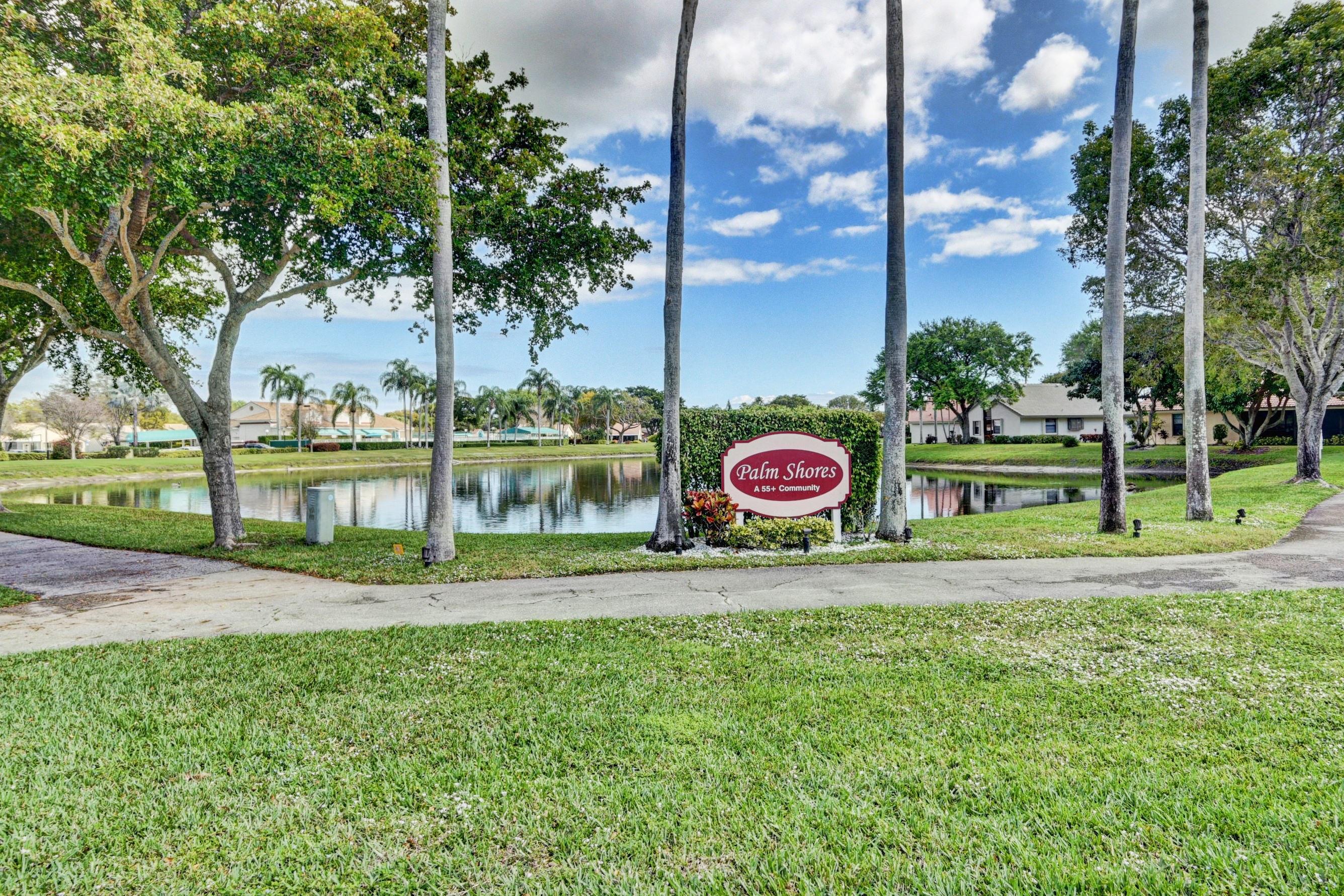 Palm Shores community sign beside a lake and landscaped entry