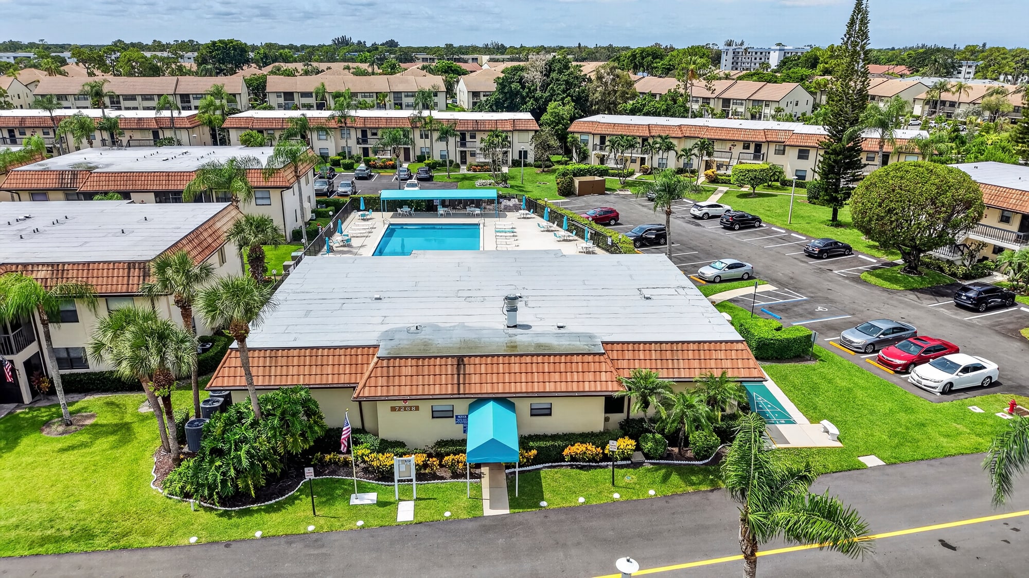 Aerial view of the Lucerne Lakes clubhouse, pool, and surrounding residences in Lake Worth, Florida