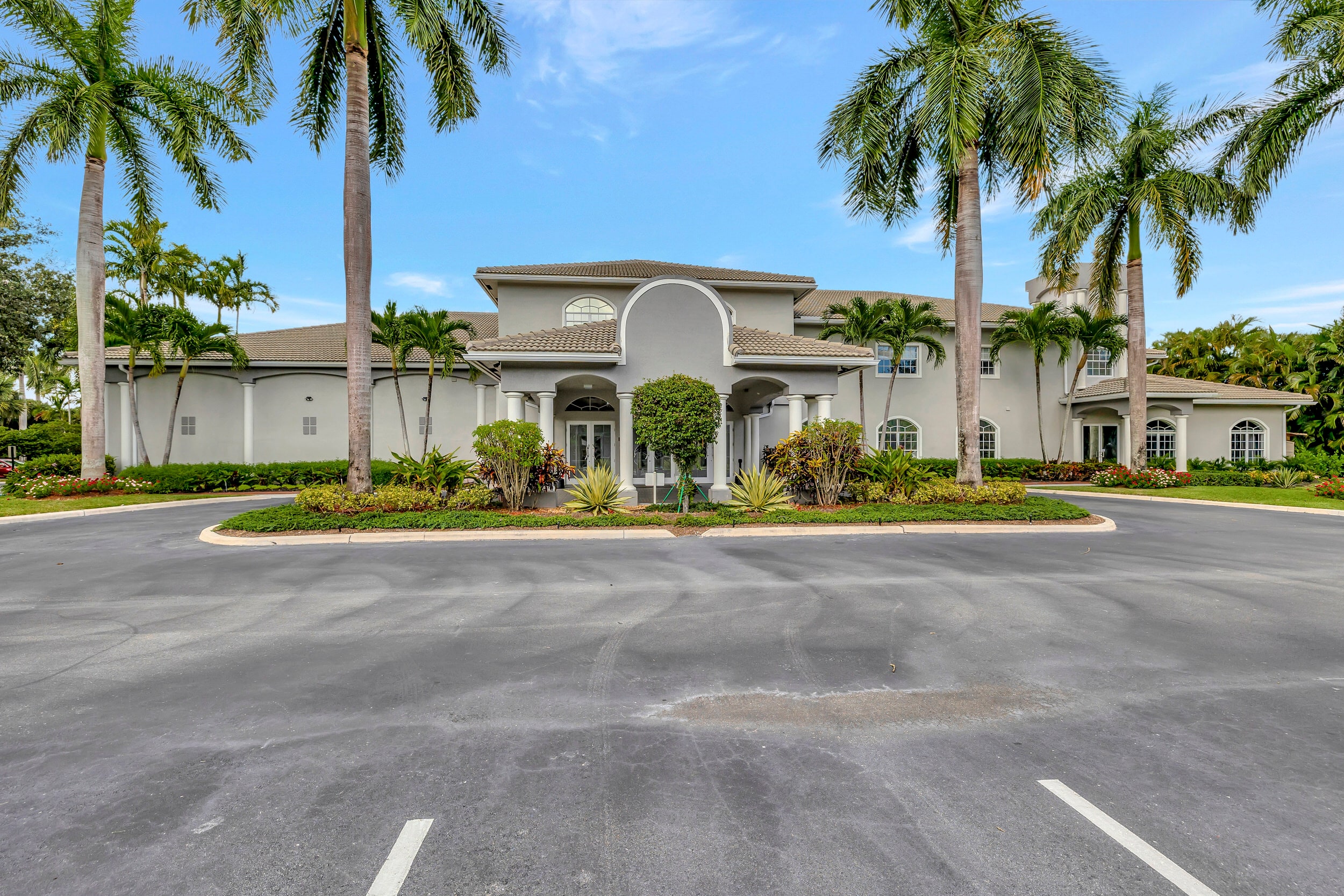 Majestic Isles clubhouse framed by palm trees and landscaped grounds in Boynton Beach