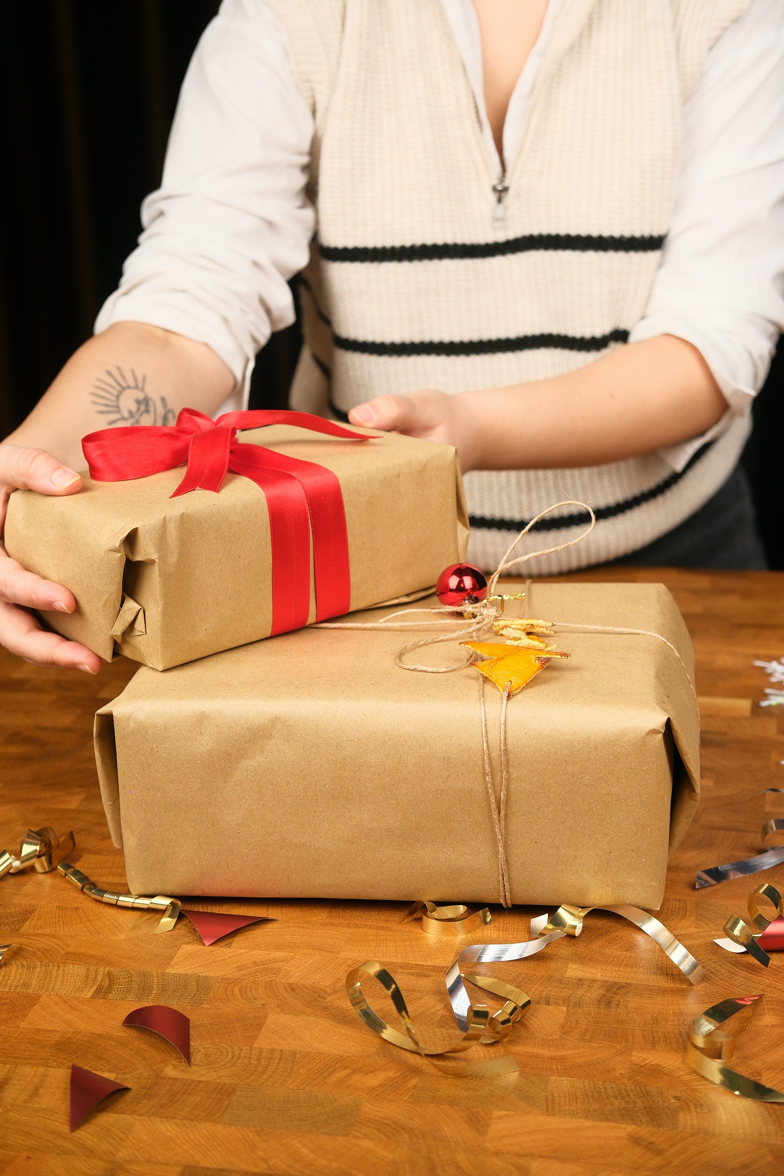 Hands wrapping brown paper gifts with ribbon