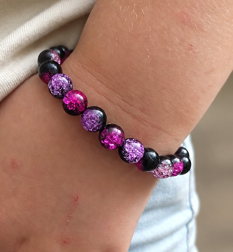 Pink Topaz pink, purple, and black beaded bracelet worn on a wrist