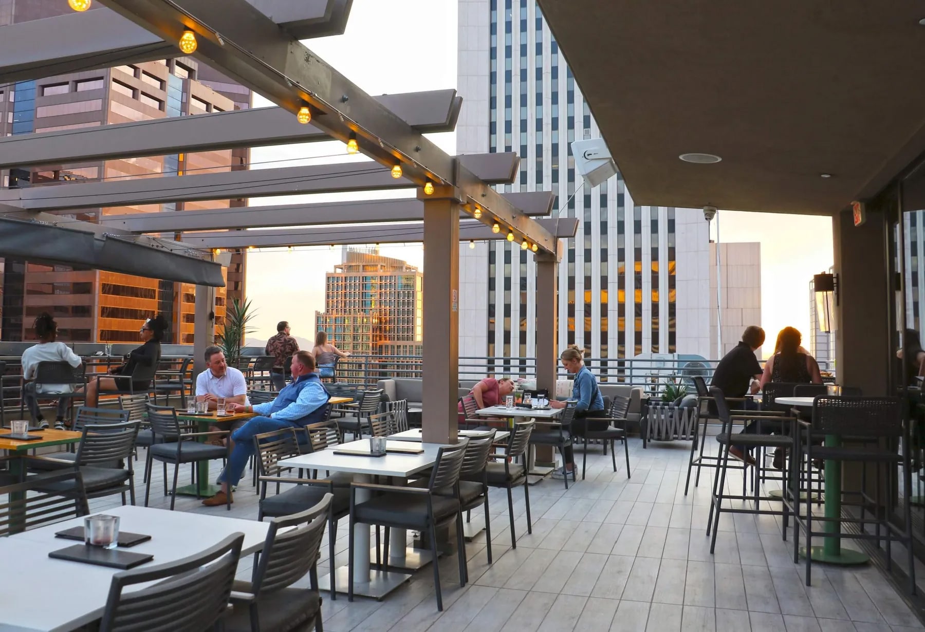 Rooftop restaurant terrace with outdoor tables and chairs at sunset