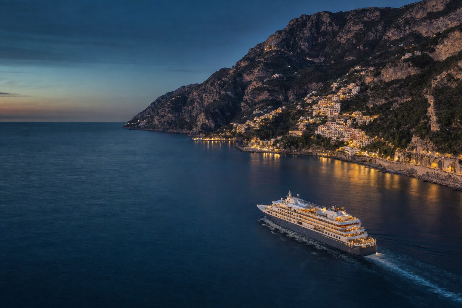 Ocean cruise ship approaching a Mediterranean coast at dusk