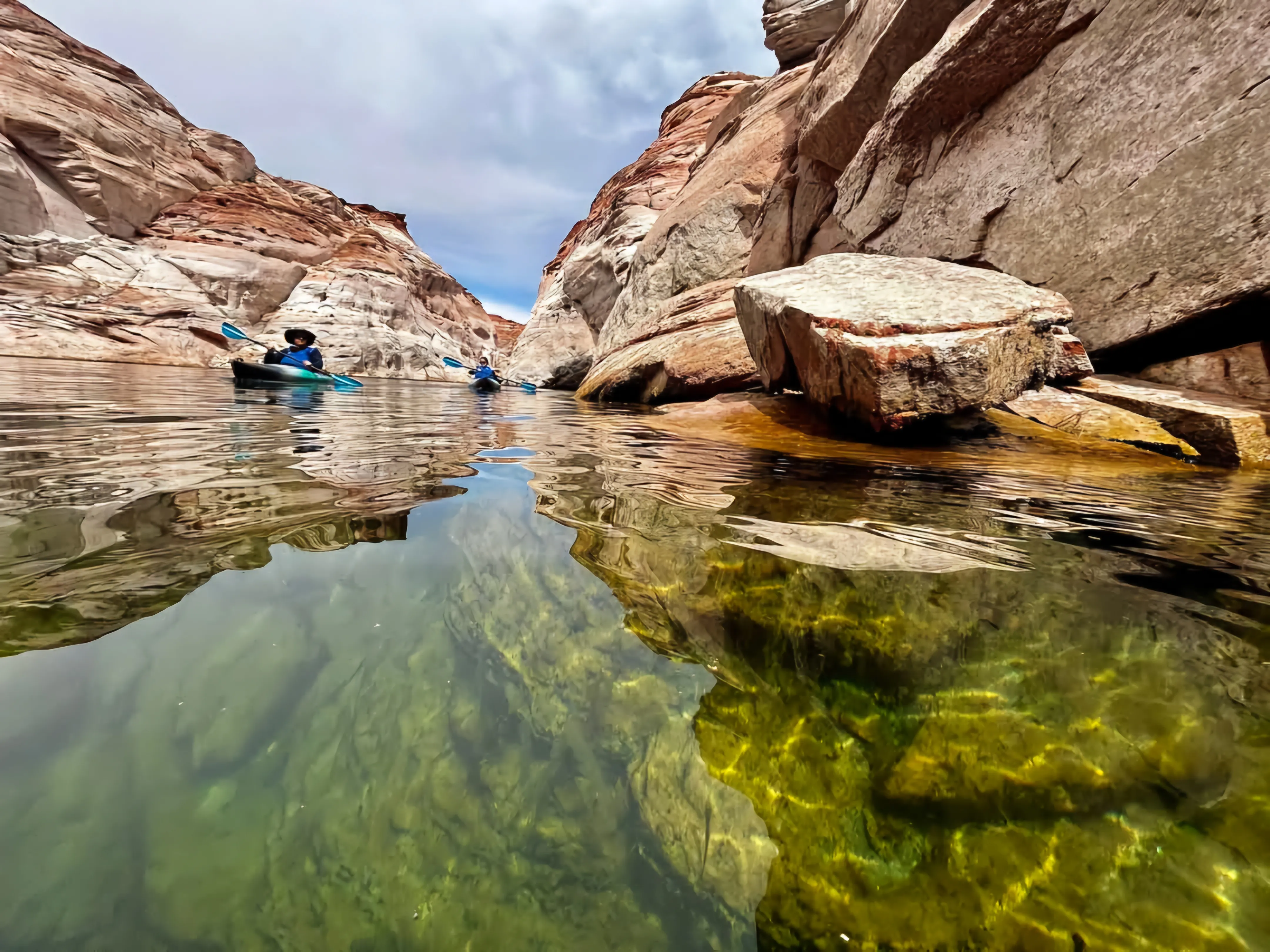 Guests walking kayaks along Lake Powell beneath red sandstone cliffs