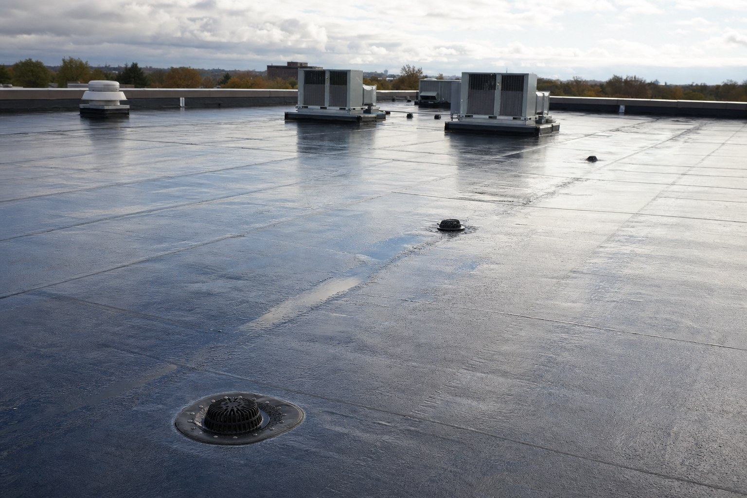Commercial roof after rain with clear drains and rooftop equipment