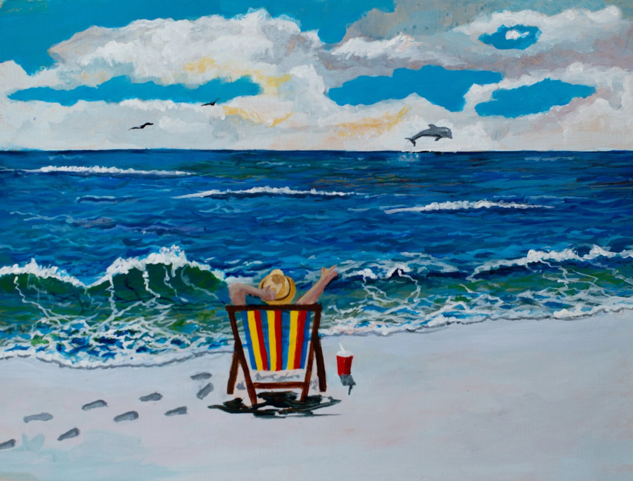 A person relaxing on a striped beach chair on the sand, facing the ocean, with a drink beside them. The water is blue with waves, and there are dolphins jumping out of the water in the distance under a partly cloudy sky.