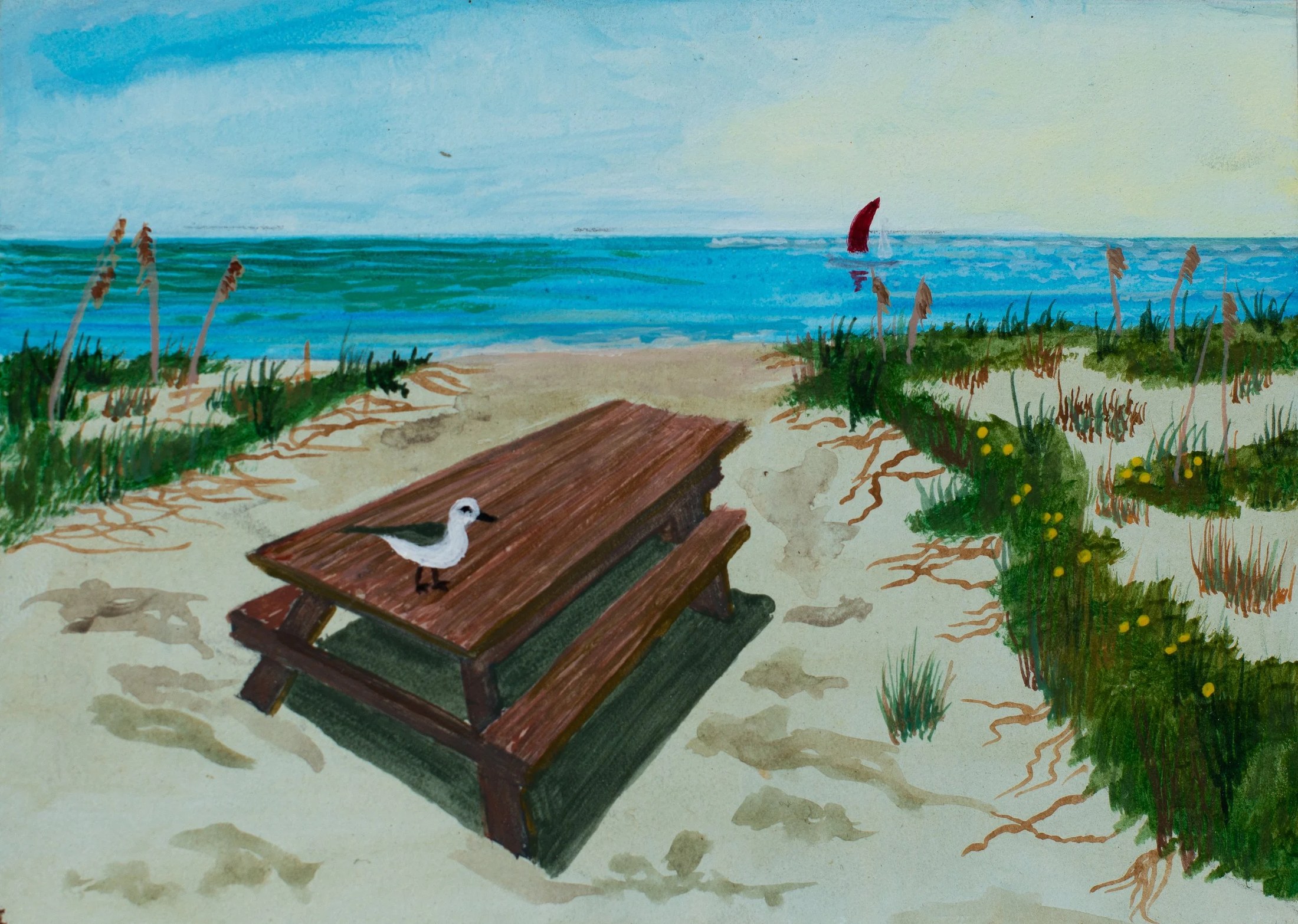 A painted beach scene with a wooden picnic table and seagull in the foreground, sandy path, grassy dunes with yellow flowers and tall grasses on either side, blue ocean with a red-sailed boat in the distance, and a partly cloudy sky.