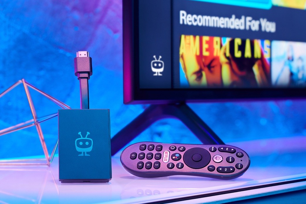 Streaming device and remote beside a television displaying a media interface