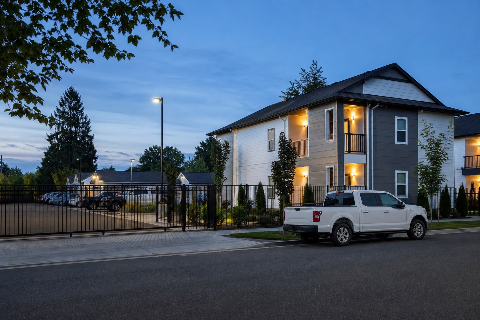 A furnished apartment building with secure parking for a work truck at early evening
