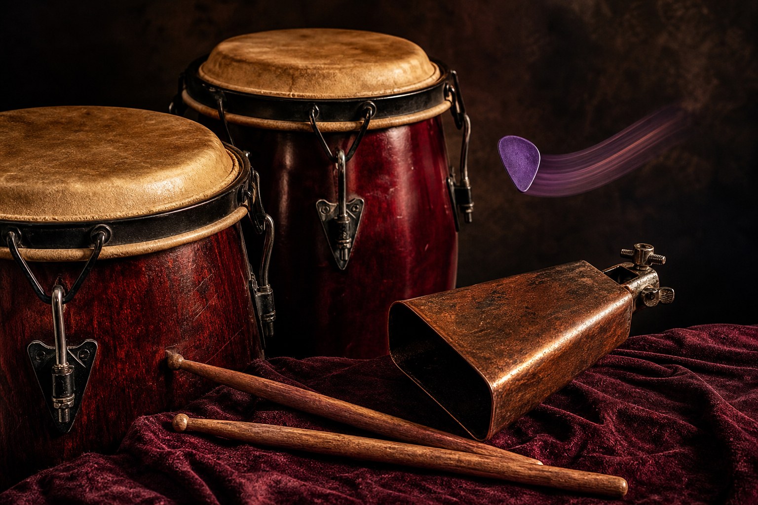 Congas, drumsticks, and cowbell arranged on deep plum fabric