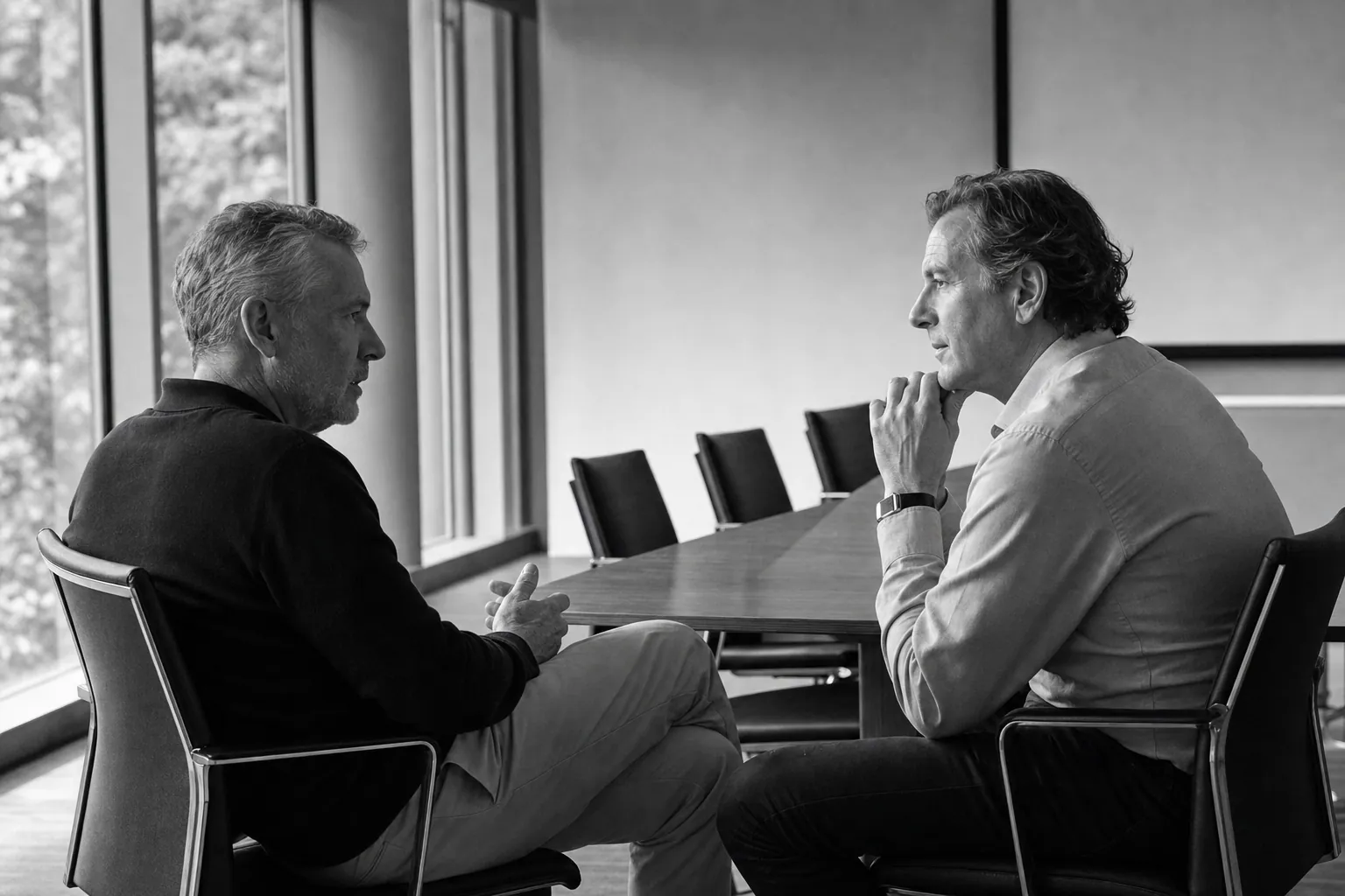 Two business leaders in a candid conversation beside a conference table