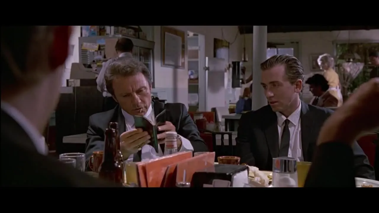Man in a suit studying a book at a table
