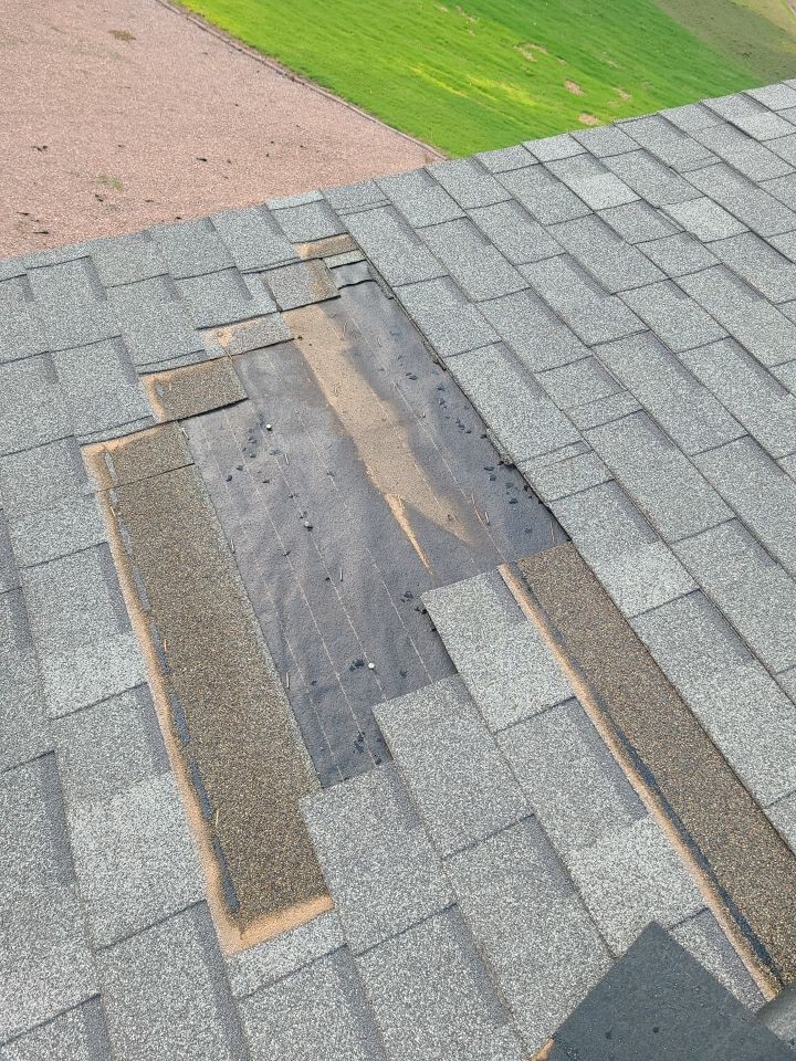 Missing gray shingles exposing the roof underlayment