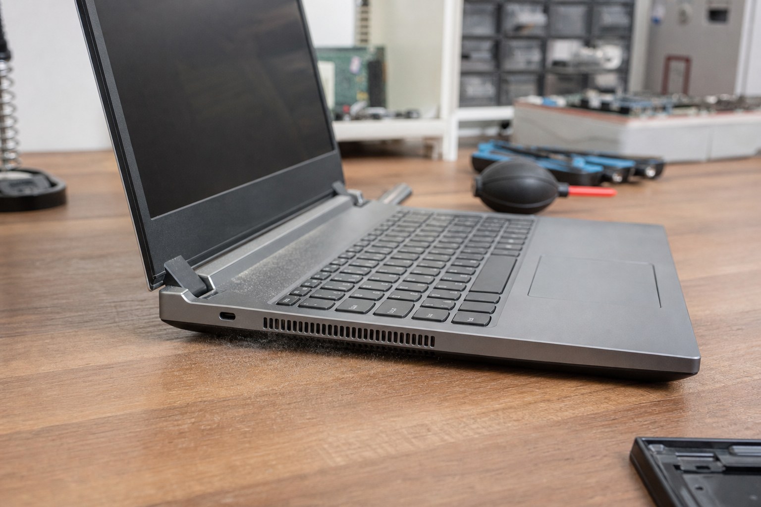 Laptop on a repair desk with cooling vents visible