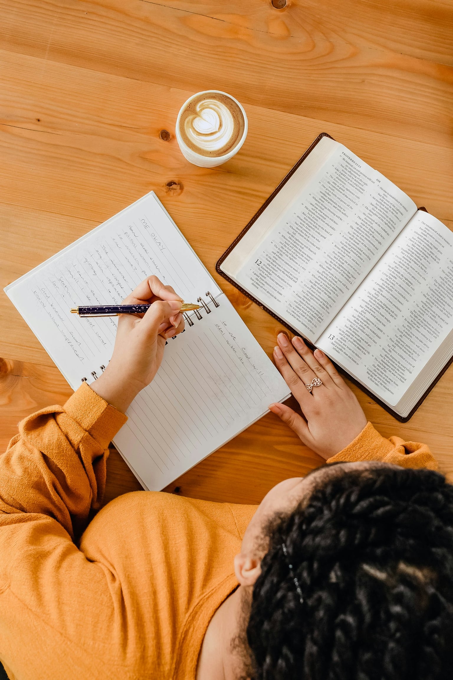Woman writing in a planner beside an open Bible and coffee