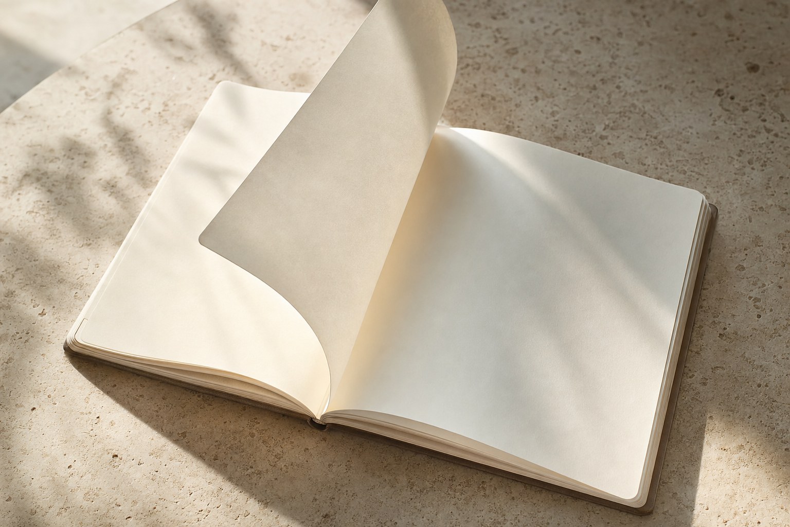 A blank ivory notebook with a page turning in soft daylight