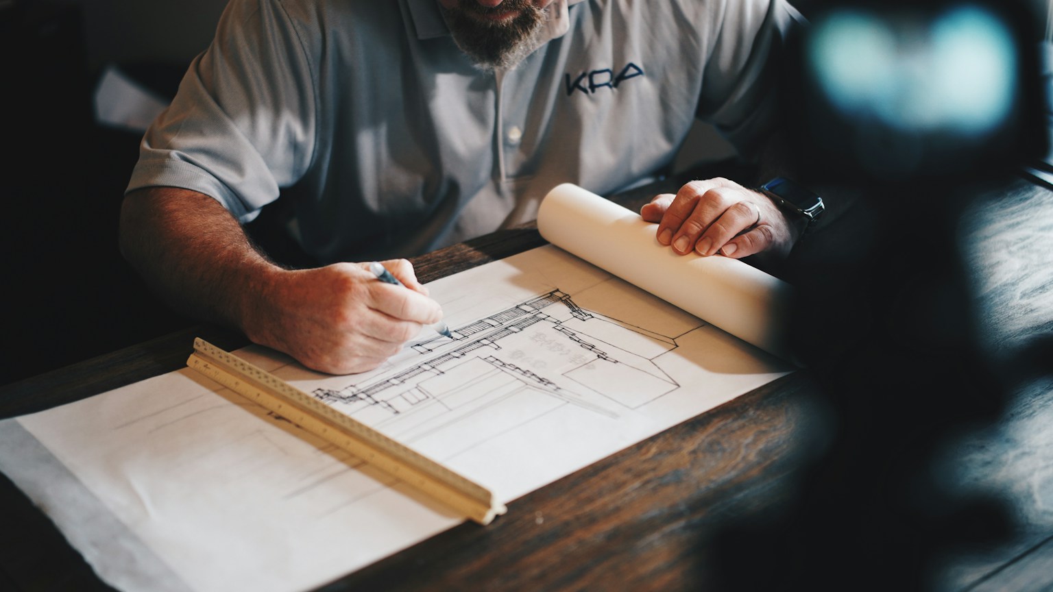 Builder marking a residential floor plan with a pencil and ruler