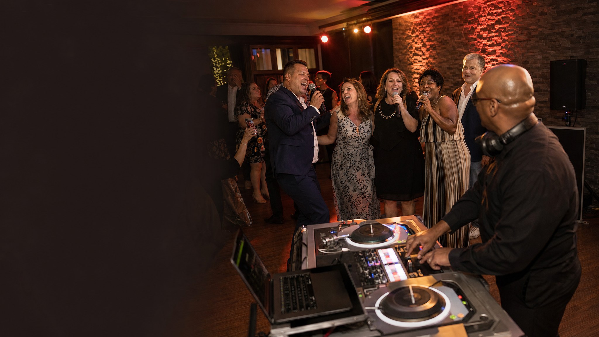 DJ performing while guests sing karaoke together at an evening event